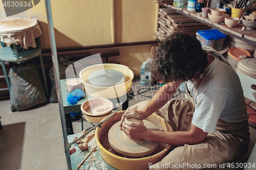 Image of Creating a jar or vase of white clay close-up. Master crock. Man hands making clay jug macro.