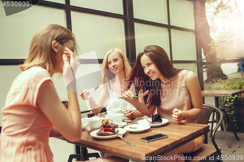 Image of Two girl friends spend time together drinking coffee in the cafe, having breakfast and dessert.