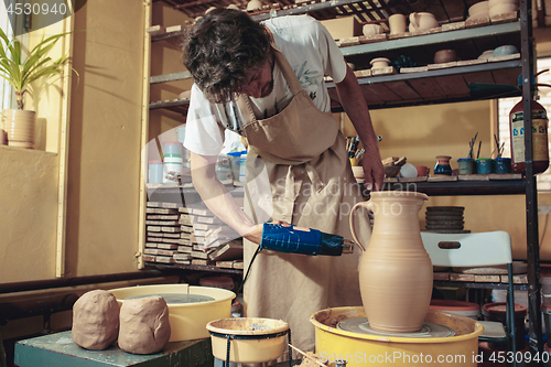 Image of Creating a jar or vase of white clay close-up. Master crock.