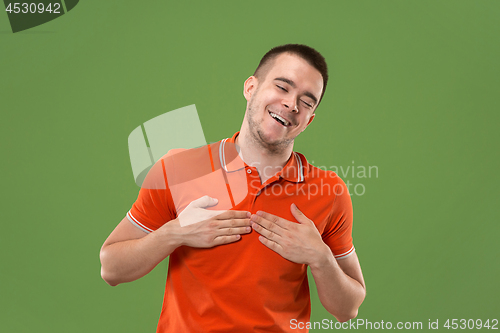 Image of Beautiful male half-length portrait isolated on green studio backgroud. The young emotional surprised man