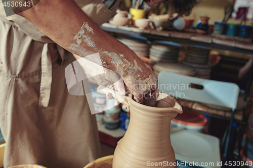 Image of Creating a jar or vase of white clay close-up. Master crock. Man hands making clay jug macro.