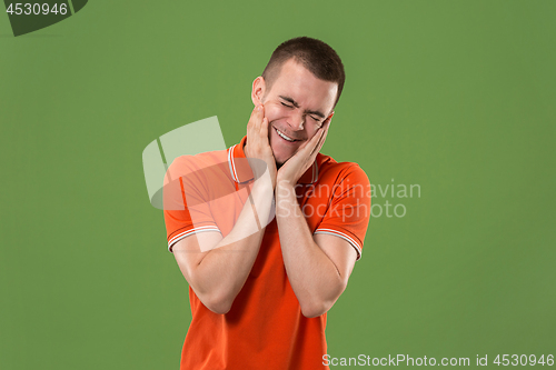 Image of Beautiful male half-length portrait isolated on green studio backgroud. The young emotional surprised man