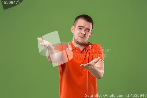 Image of Beautiful male half-length portrait isolated on green studio backgroud. The young emotional surprised man