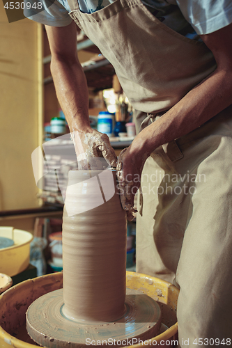 Image of Creating a jar or vase of white clay close-up. Master crock. Man hands making clay jug macro.