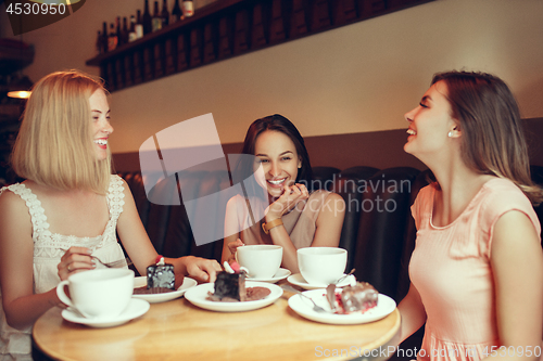 Image of Two girl friends spend time together drinking coffee in the cafe, having breakfast and dessert.