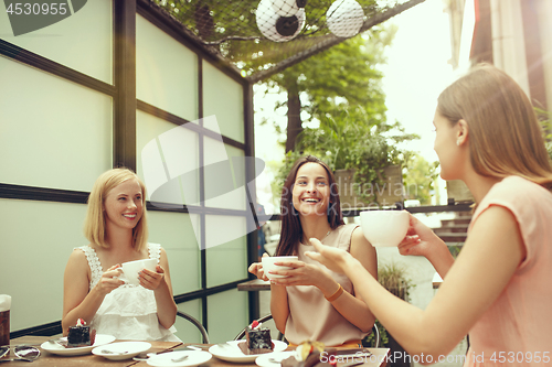 Image of Two girl friends spend time together drinking coffee in the cafe, having breakfast and dessert.