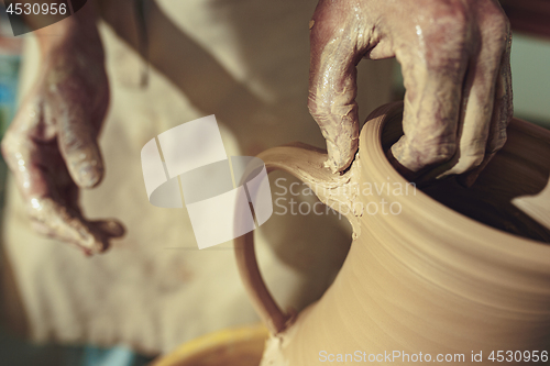 Image of Creating a jar or vase of white clay close-up. Master crock. Man hands making clay jug macro.