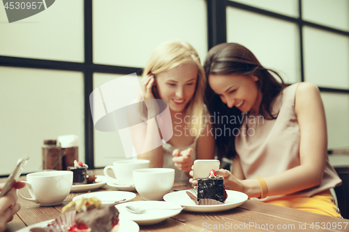 Image of Two girl friends spend time together drinking coffee in the cafe, having breakfast and dessert.