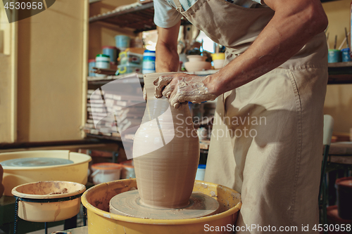 Image of Creating a jar or vase of white clay close-up. Master crock. Man hands making clay jug macro.