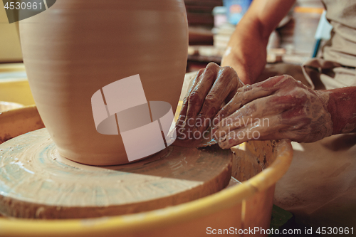 Image of Creating a jar or vase of white clay close-up. Master crock. Man hands making clay jug macro.