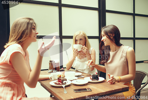 Image of Two girl friends spend time together drinking coffee in the cafe, having breakfast and dessert.