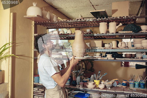 Image of Creating a jar or vase of white clay close-up. Master crock.