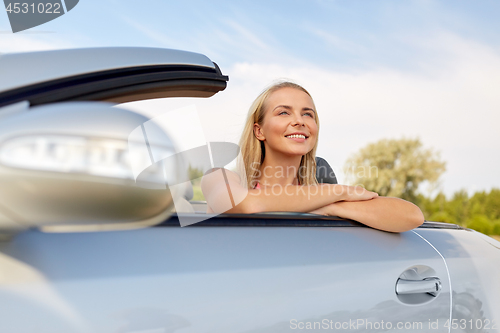 Image of happy young woman in convertible car