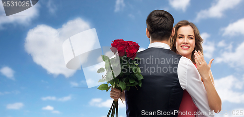 Image of woman with engagement ring and roses hugging man