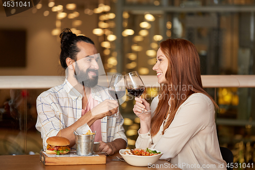 Image of couple eating and drinking red wine at restaurant