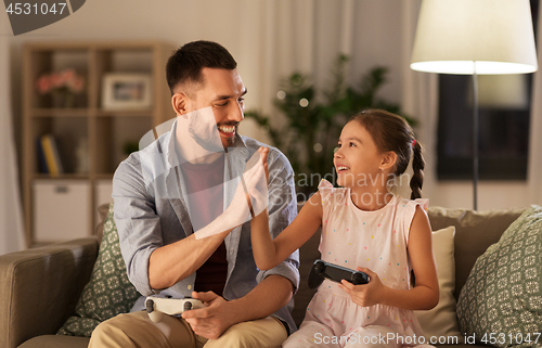 Image of father and daughter playing video game at home