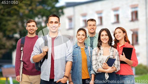 Image of group of smiling students with books over campus