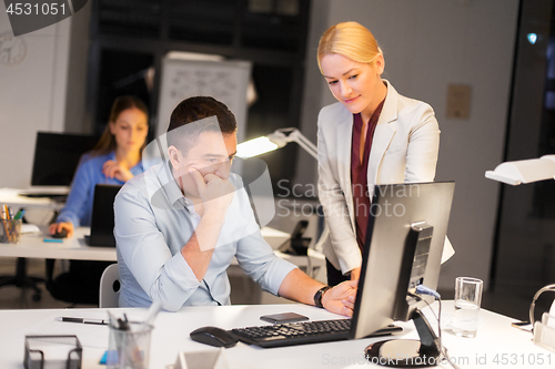 Image of business team with computer working late at office