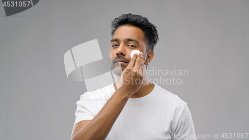 Image of smiling indian man cleaning face with cotton pad