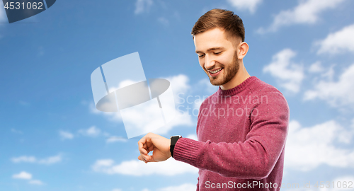 Image of smiling young man checking time on wristwatch