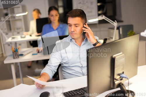 Image of man calling on smartphone at night office