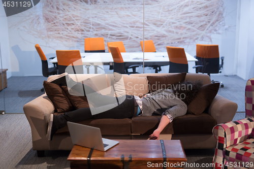 Image of man sleeping on a sofa  in a creative office