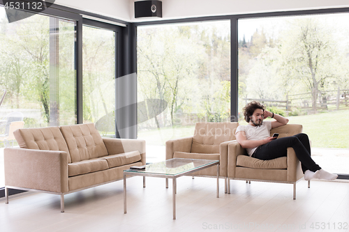 Image of young man using a mobile phone  at home