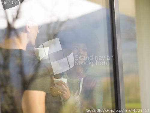 Image of happy multiethnic couple relaxing at modern home indoors