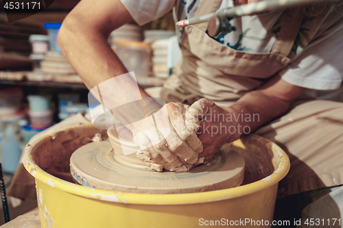 Image of Creating a jar or vase of white clay close-up. Master crock. Man hands making clay jug macro.