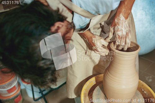 Image of Creating a jar or vase of white clay close-up. Master crock.