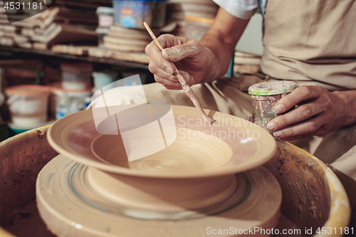 Image of Creating a jar or vase of white clay close-up. Master crock. Man hands making clay jug macro.