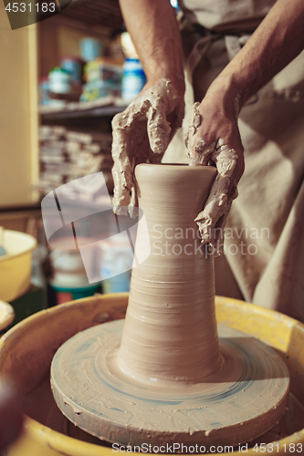 Image of Creating a jar or vase of white clay close-up. Master crock. Man hands making clay jug macro.