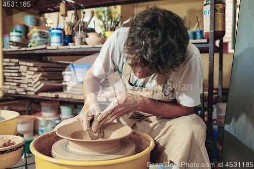 Image of Creating a jar or vase of white clay close-up. Master crock.