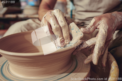 Image of Creating a jar or vase of white clay close-up. Master crock. Man hands making clay jug macro.