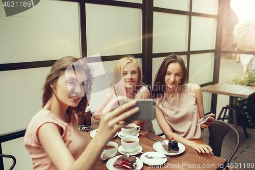 Image of Two girl friends spend time together drinking coffee in the cafe, having breakfast and dessert.