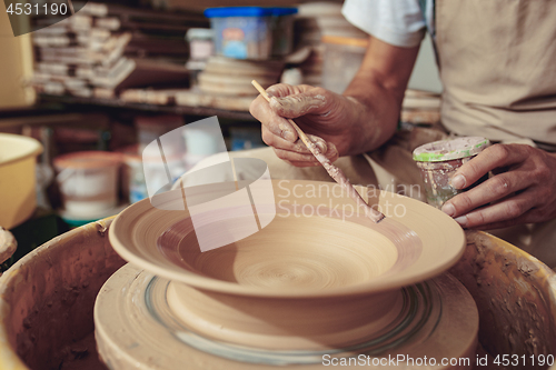 Image of Creating a jar or vase of white clay close-up. Master crock. Man hands making clay jug macro.