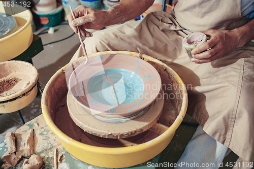 Image of Creating a jar or vase of white clay close-up. Master crock. Man hands making clay jug macro.