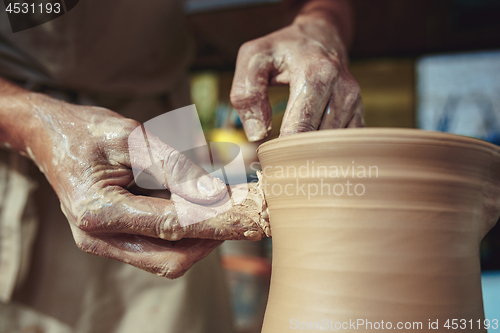 Image of Creating a jar or vase of white clay close-up. Master crock. Man hands making clay jug macro.