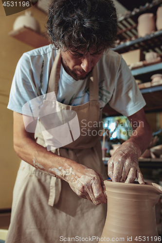 Image of Creating a jar or vase of white clay close-up. Master crock.