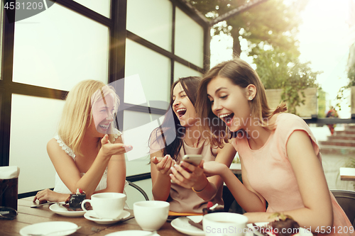 Image of Two girl friends spend time together drinking coffee in the cafe, having breakfast and dessert.