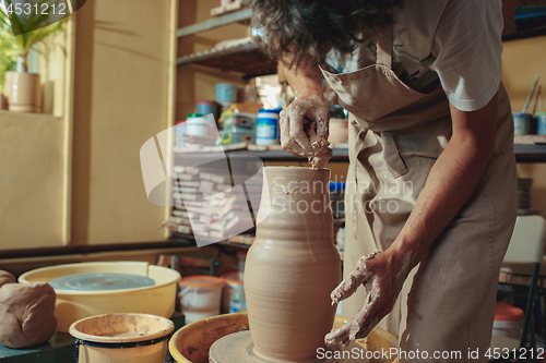 Image of Creating a jar or vase of white clay close-up. Master crock. Man hands making clay jug macro.