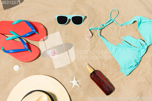 Image of straw hat, flip flops and sunglasses on beach sand