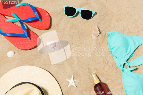 Image of straw hat, flip flops and sunglasses on beach sand