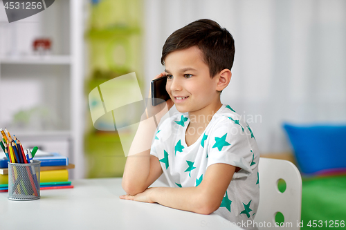 Image of happy boy calling on smartphone at home