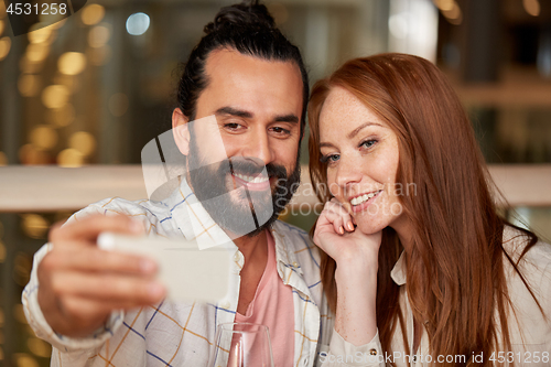 Image of couple taking selfie by smartphone at restaurant