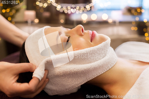 Image of woman having face massage with towel at spa