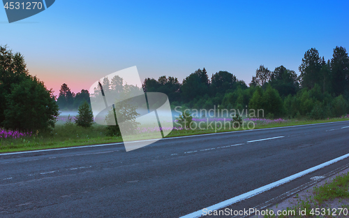 Image of Empty Asphalt Road Among Misty Flowering Meadows In A Morning Tw