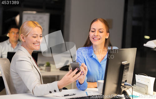 Image of businesswomen with smartphone late at night office