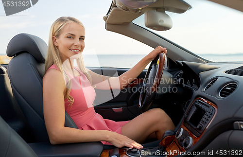 Image of happy young woman driving convertible car