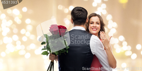 Image of woman with engagement ring and roses hugging man